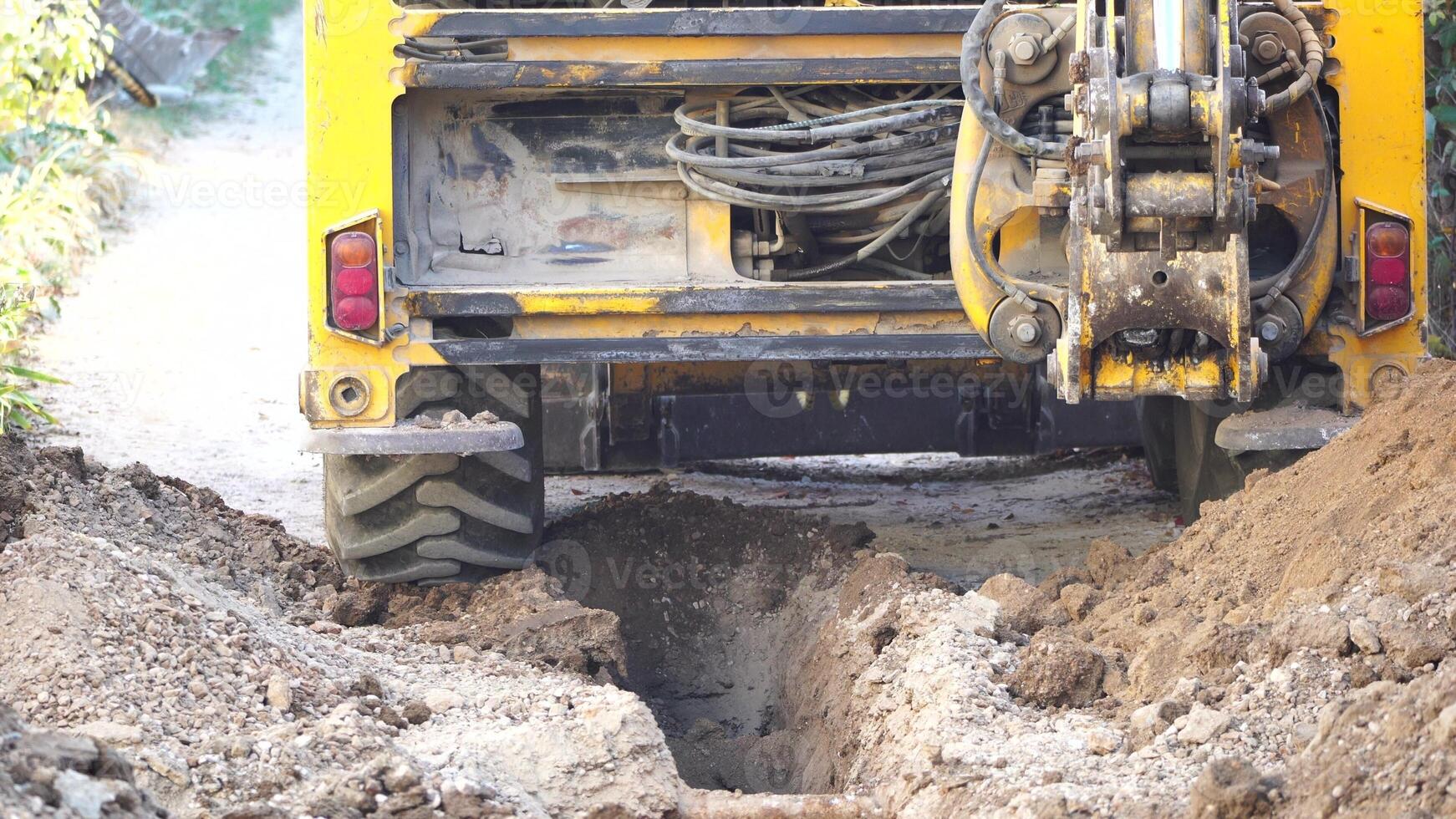 excavador alojamiento un zanja a laico tubería. cerca arriba de un excavador excavación un profundo zanja. un excavador alojamiento un zanja en el campo a laico un agua tubo. foto