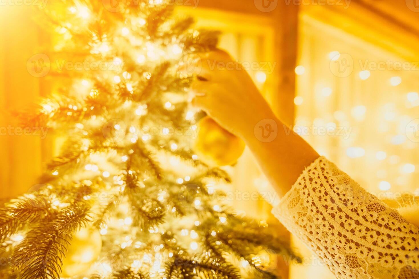 Woman decorate A Christmas tree with gold ornaments and lights. The tree is decorated with gold balls and is lit up with lights. photo