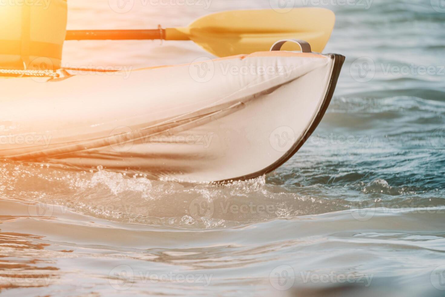 Happy couple kayaks in an inflatable kayak on the sea at sunset. Couple kanoeing in the sea near the island with mountains. People kayaking in life jackets sail. Back view photo