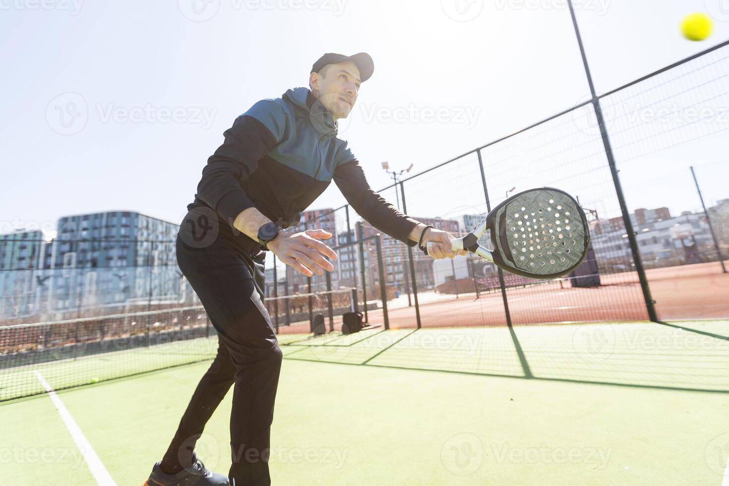 Young padel player trains by catching high balls photo