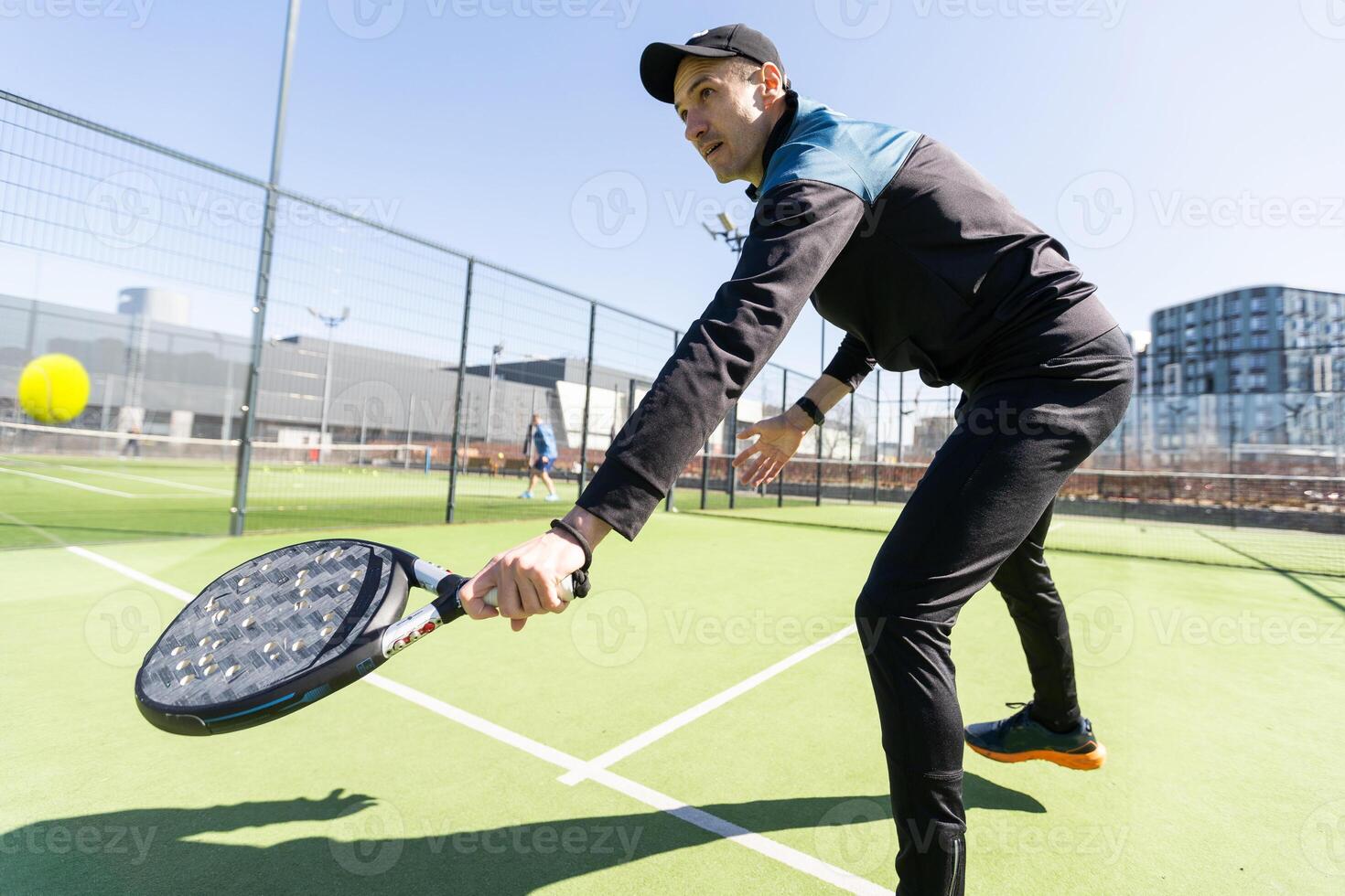 Man playing padel in a green grass padel court indoor behind the net photo