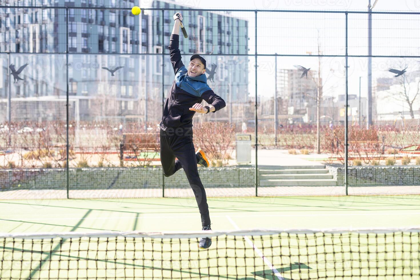 Young padel player trains by catching high balls photo