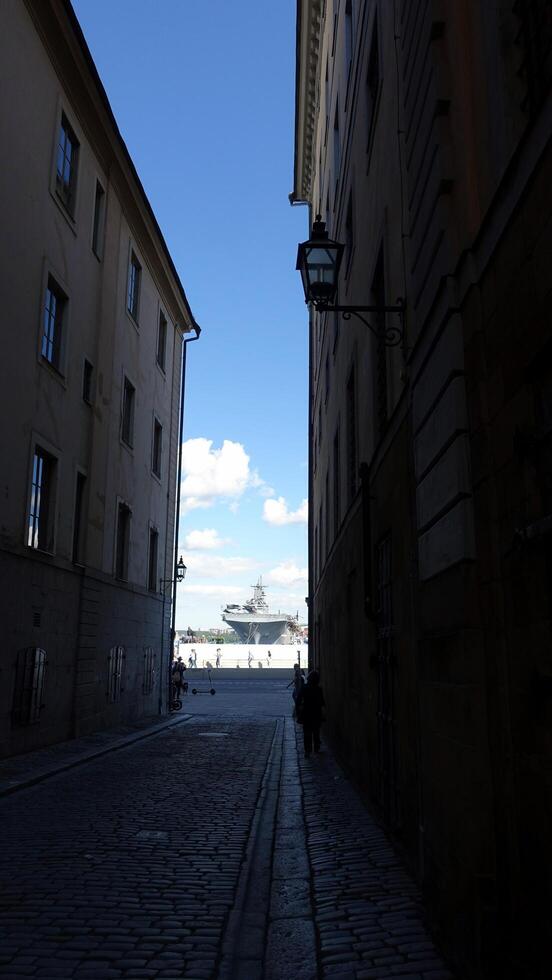 Stockholm, Sweden, June 4, 2022 A warship in the bay can be seen from a small street photo