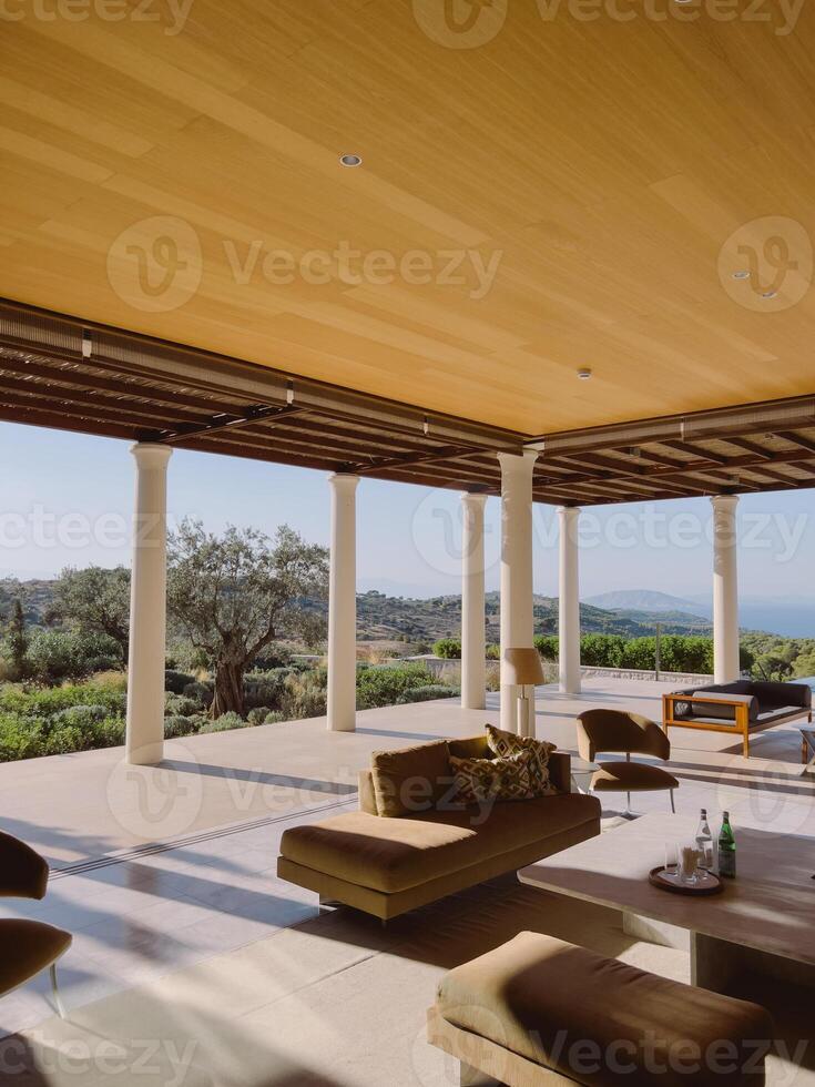 Lounge area with soft sofas and armchairs on an open terrace with columns. Hotel Amanzoe, Greece photo
