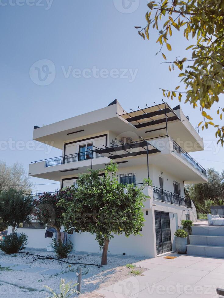 Two-storey cottage with terraces in the garden against the blue sky photo