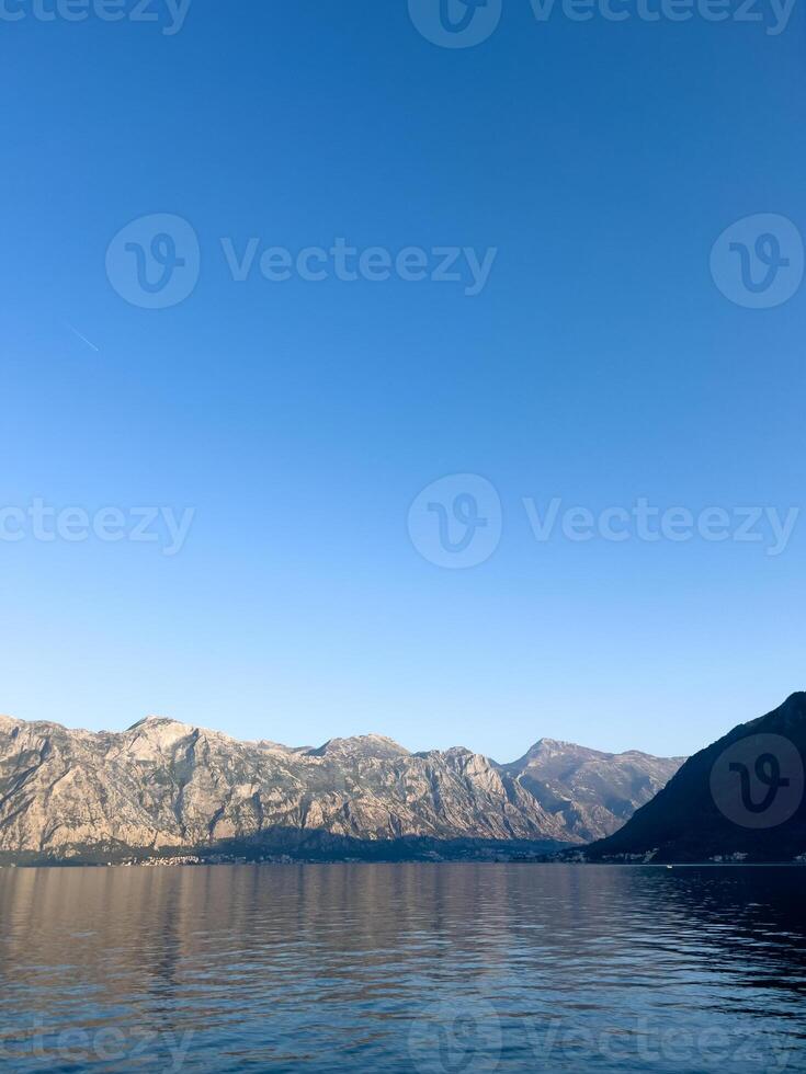 High mountain range by the sea against a clear blue sky photo