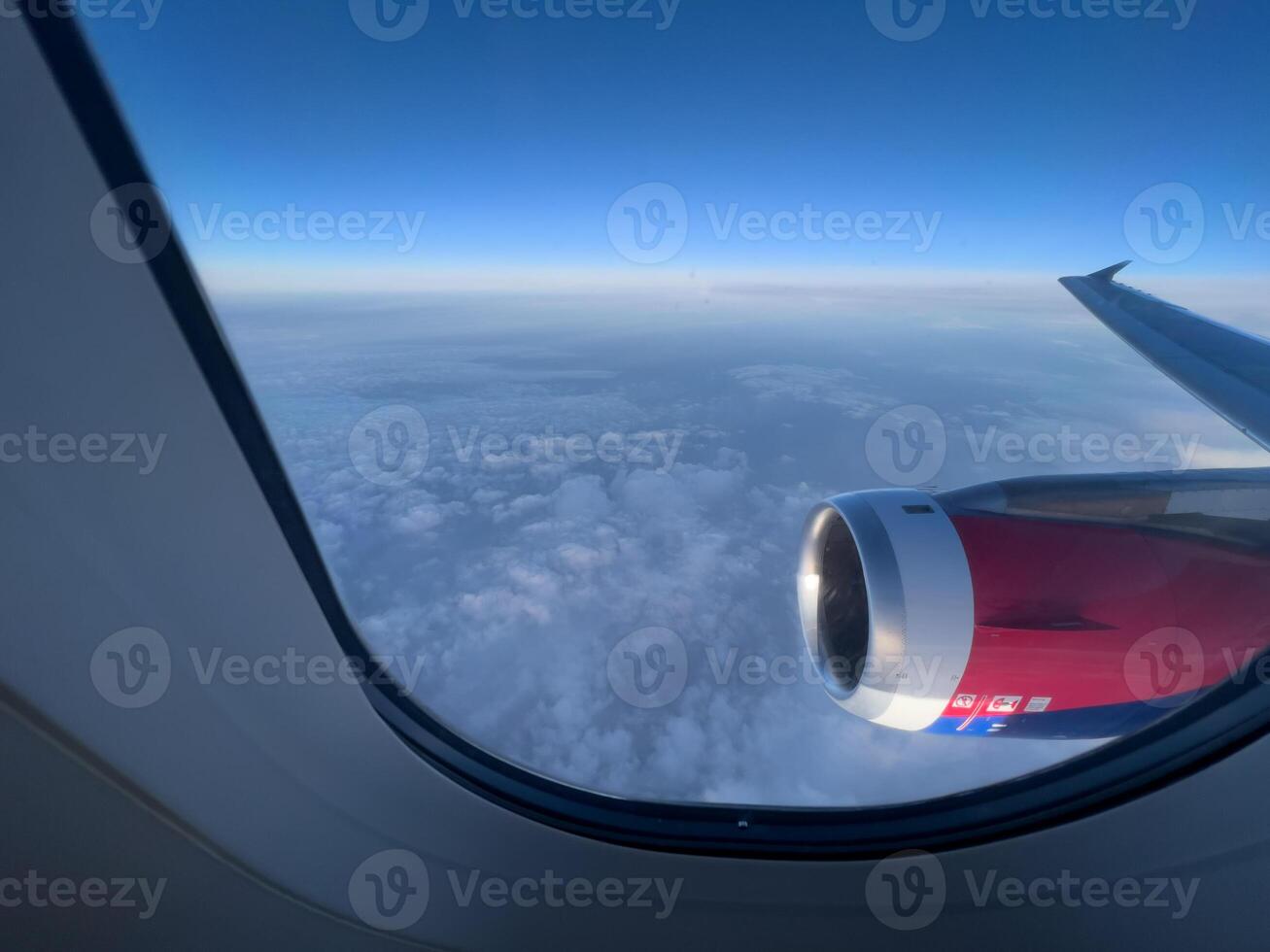 View from the window on the turbine and the wing of an airplane flying above the clouds photo