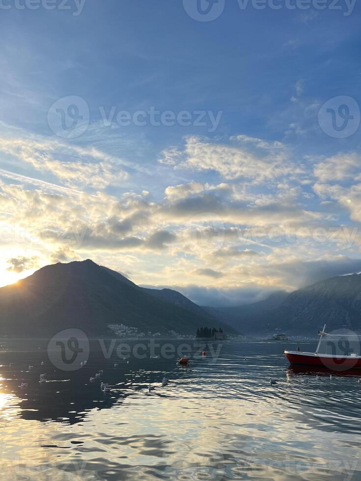 pescar barco en el mar en contra el fondo de un montaña rango y puesta de sol cielo foto