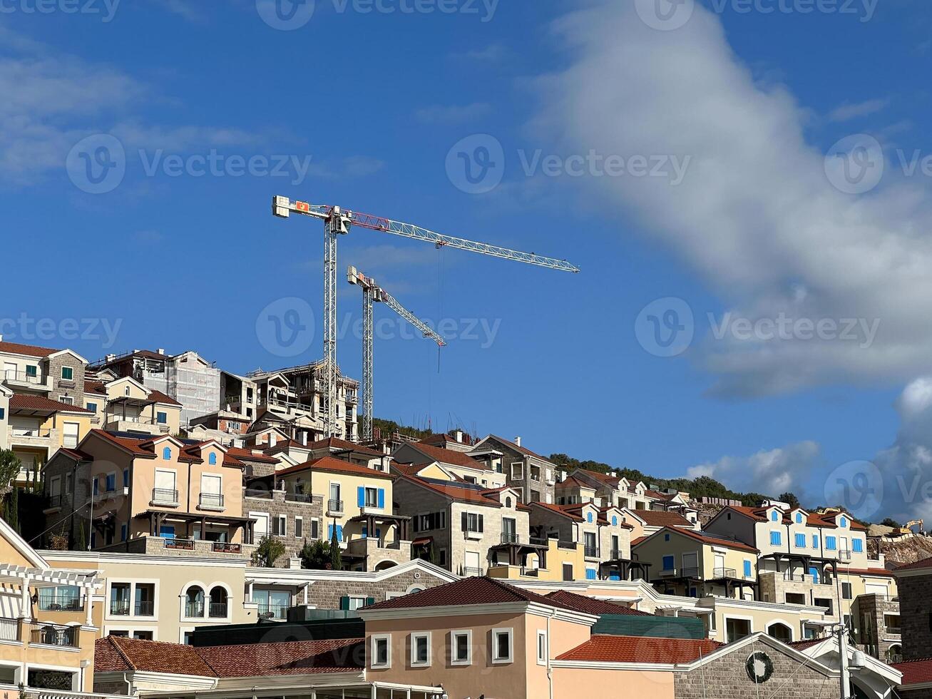 Construction cranes stand over colorful houses on the mountain photo