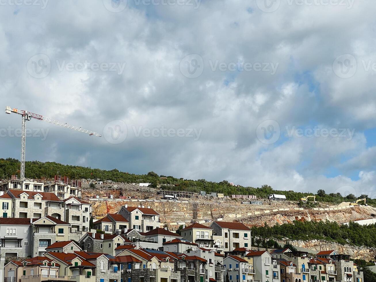 Construction crane over colorful buildings with red roofs on a mountain slope photo