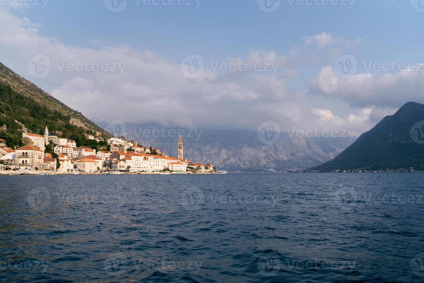 ver desde el mar a el antiguo pueblo de perast a el pie de un alto montaña rango. montenegro foto