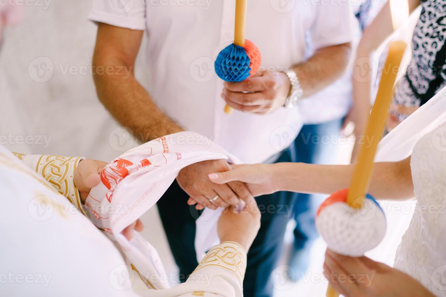 Priest ties an embroidered towel around the hands of the bride and groom photo