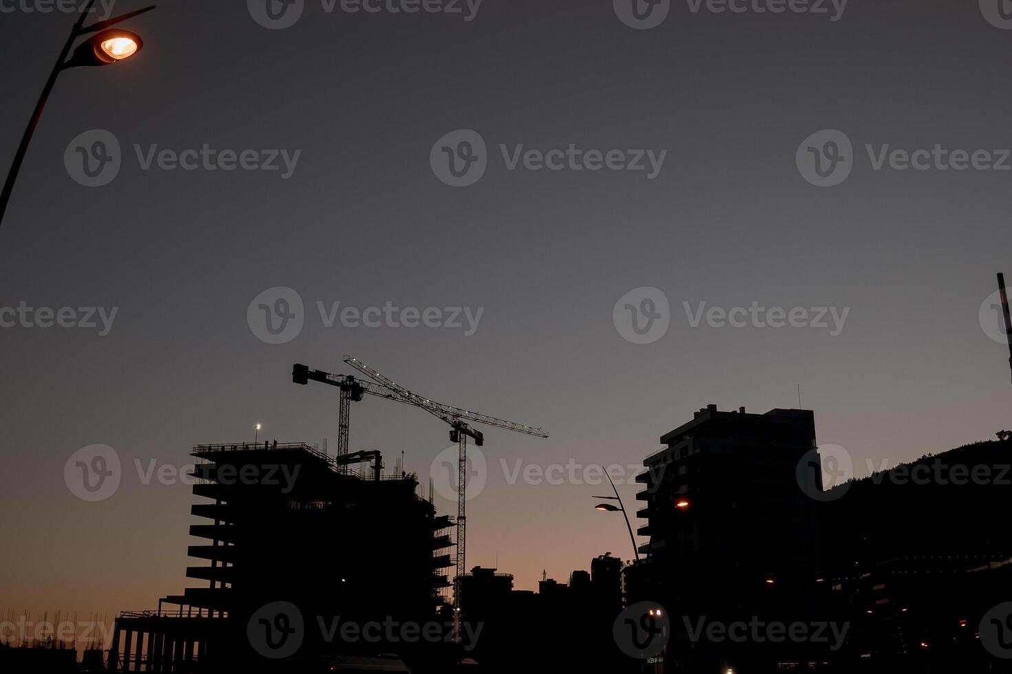 Silhouettes of tower cranes at the construction site of high-rise buildings at sunset photo