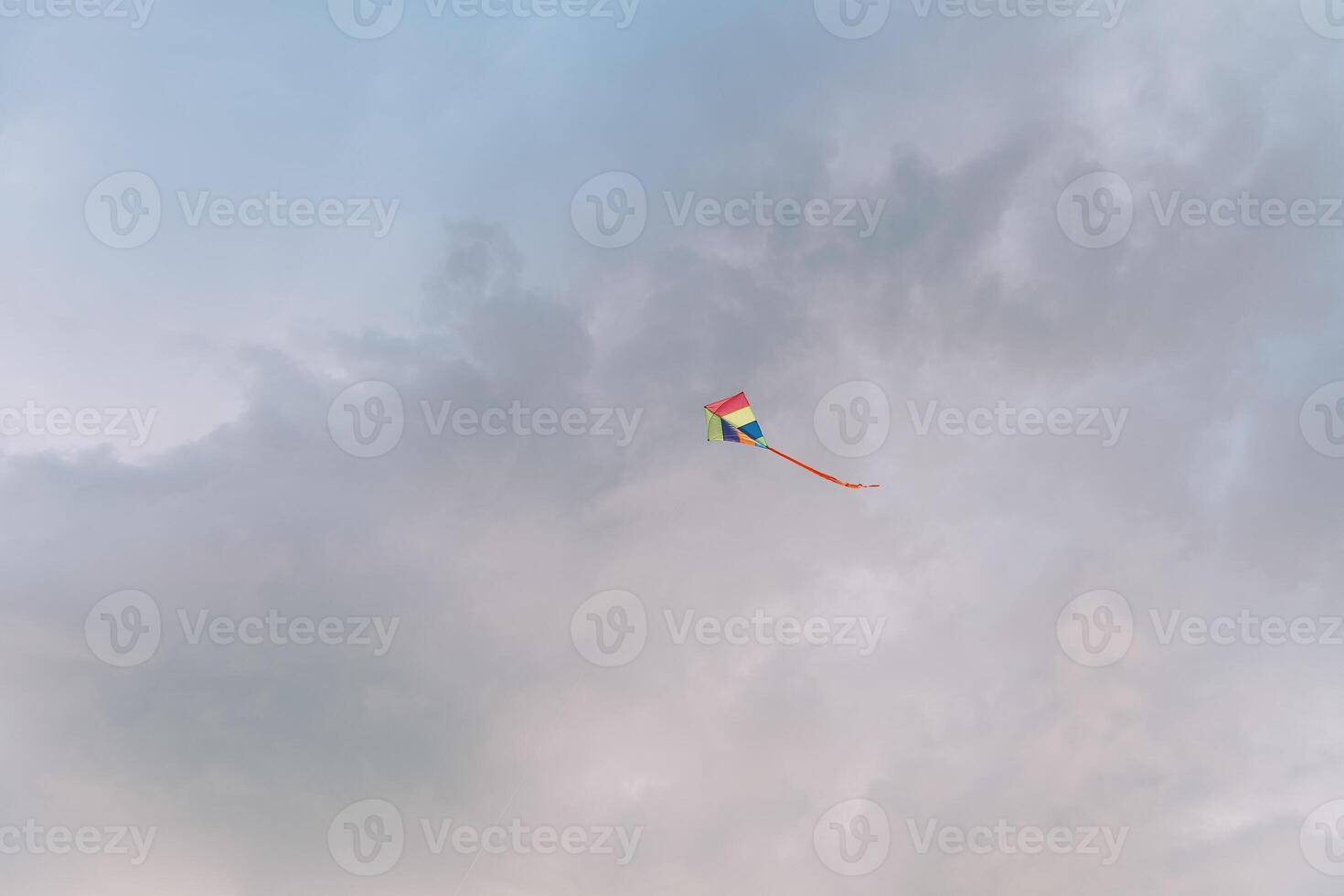 Multicolored kite soars in the cloudy sky photo