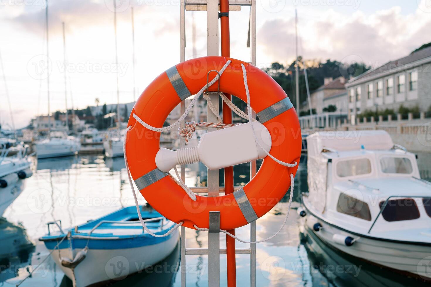 Orange lifebuoy on a metal stand with a plastic retainer on the pier photo