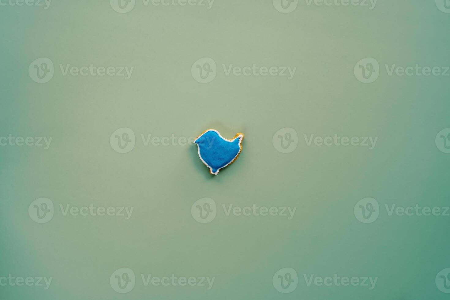 Blue glazed cookie in the shape of a bird on a green background photo