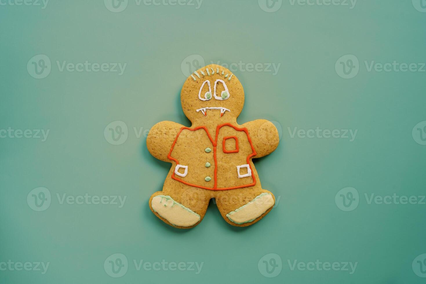 Glazed gingerbread man vampire lies centered on a green background photo