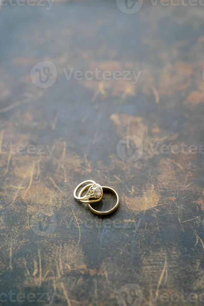 Wedding rings lie on a scratched painted table photo