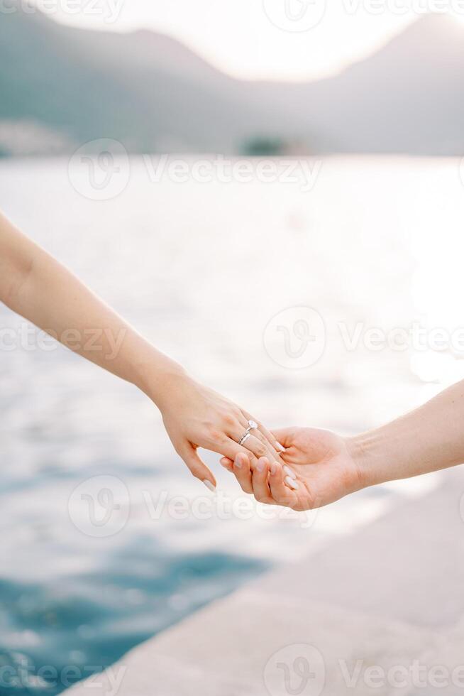 Woman hand touches man hand on the seashore. Cropped. Faceless photo