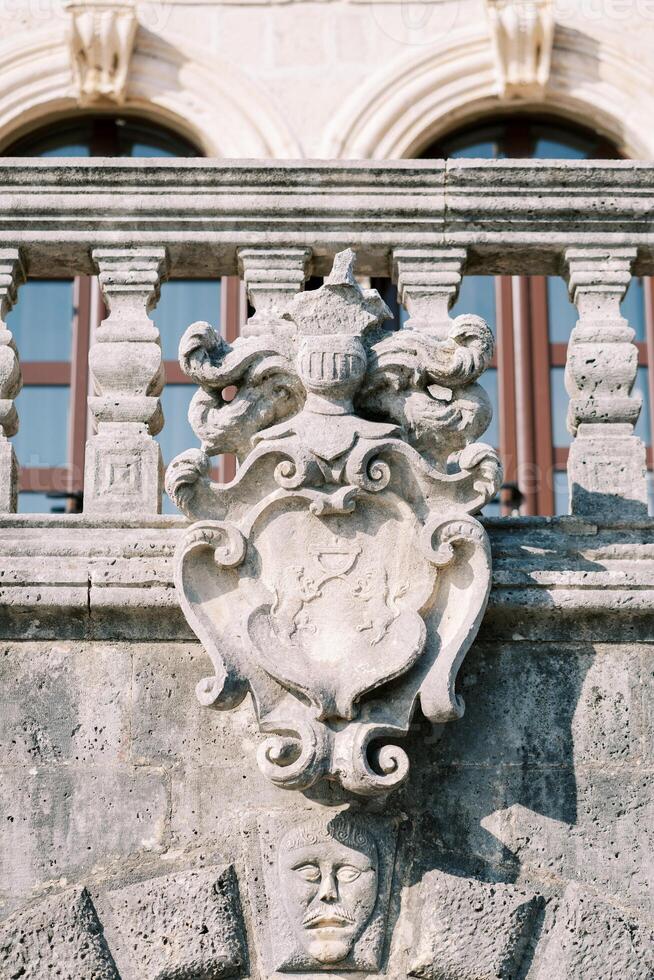 Antique carved stone coat of arms on the balustrade of an old building photo