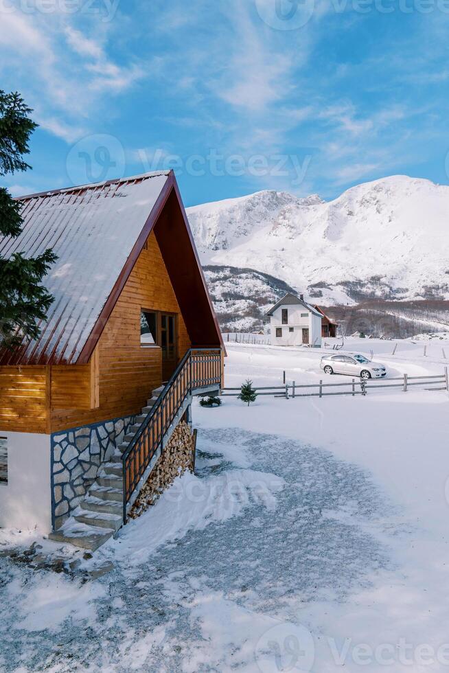 de madera cubierto de nieve dos pisos cabaña en un pequeño pueblo en un montaña Valle foto