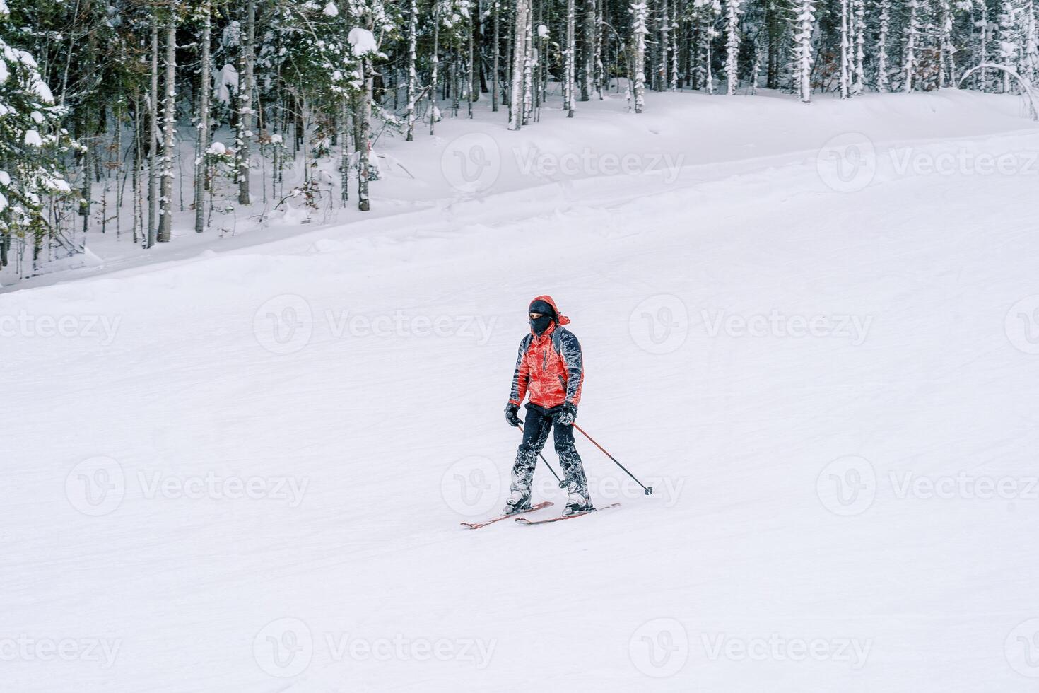 Skier in a red ski suit rides down the slope of a snowy mountain photo