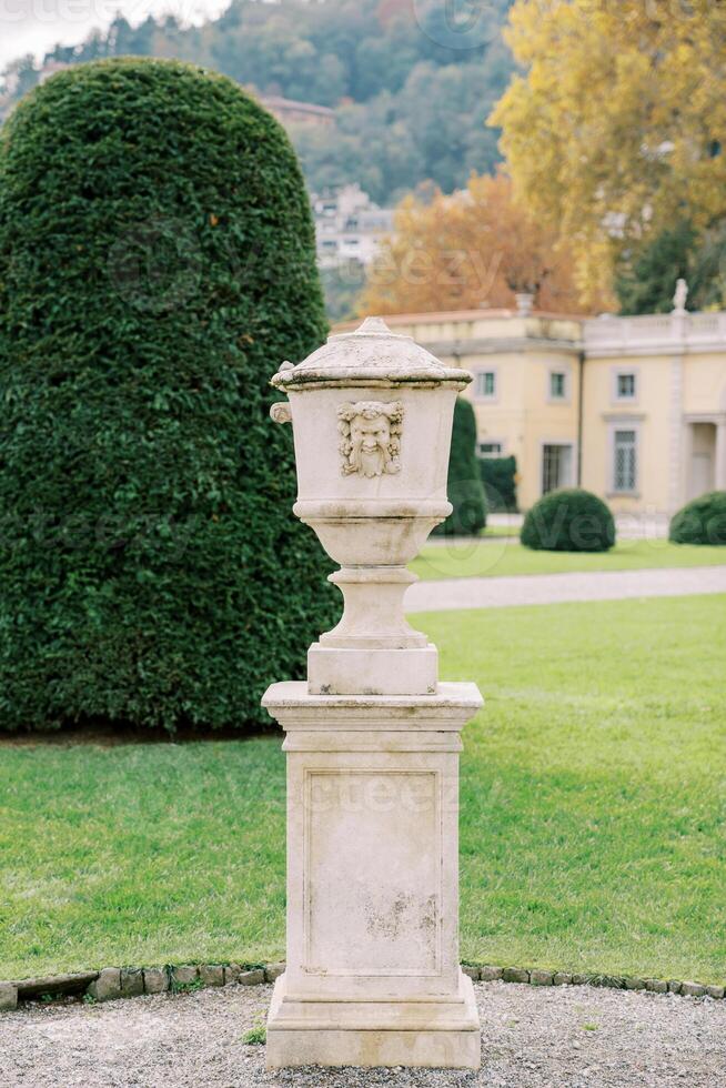 Marble flowerpot with lid in the green garden of an ancient villa photo