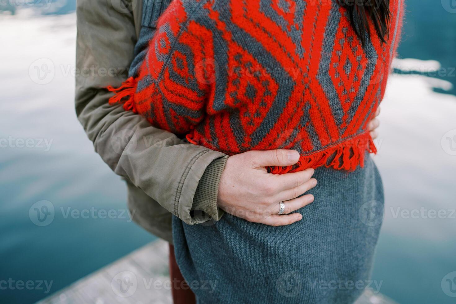 Man hugs woman waist while standing on a pier by the sea. Cropped. Faceless photo