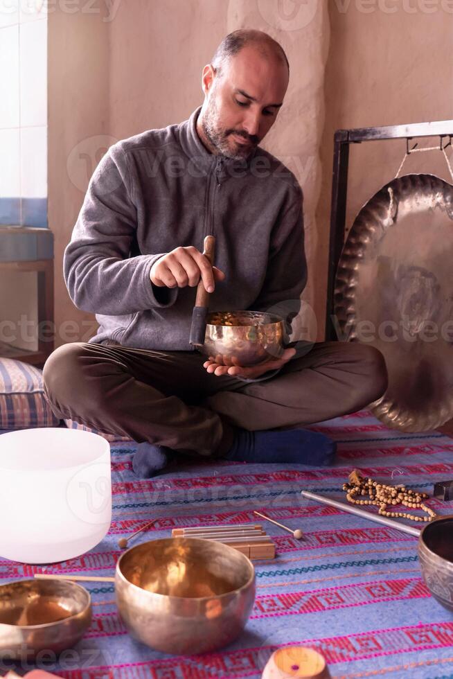 Focused Latino man playing a Tibetan singing bowl. photo