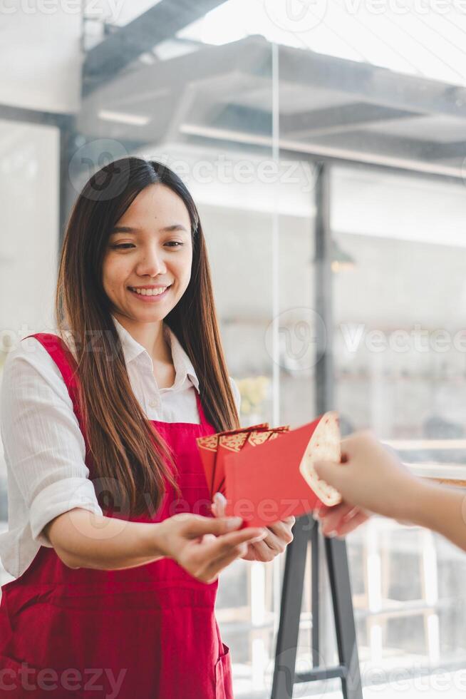 A woman with a beaming smile receives a red envelope, a gesture steeped in cultural significance, conveying blessings and good fortune. photo