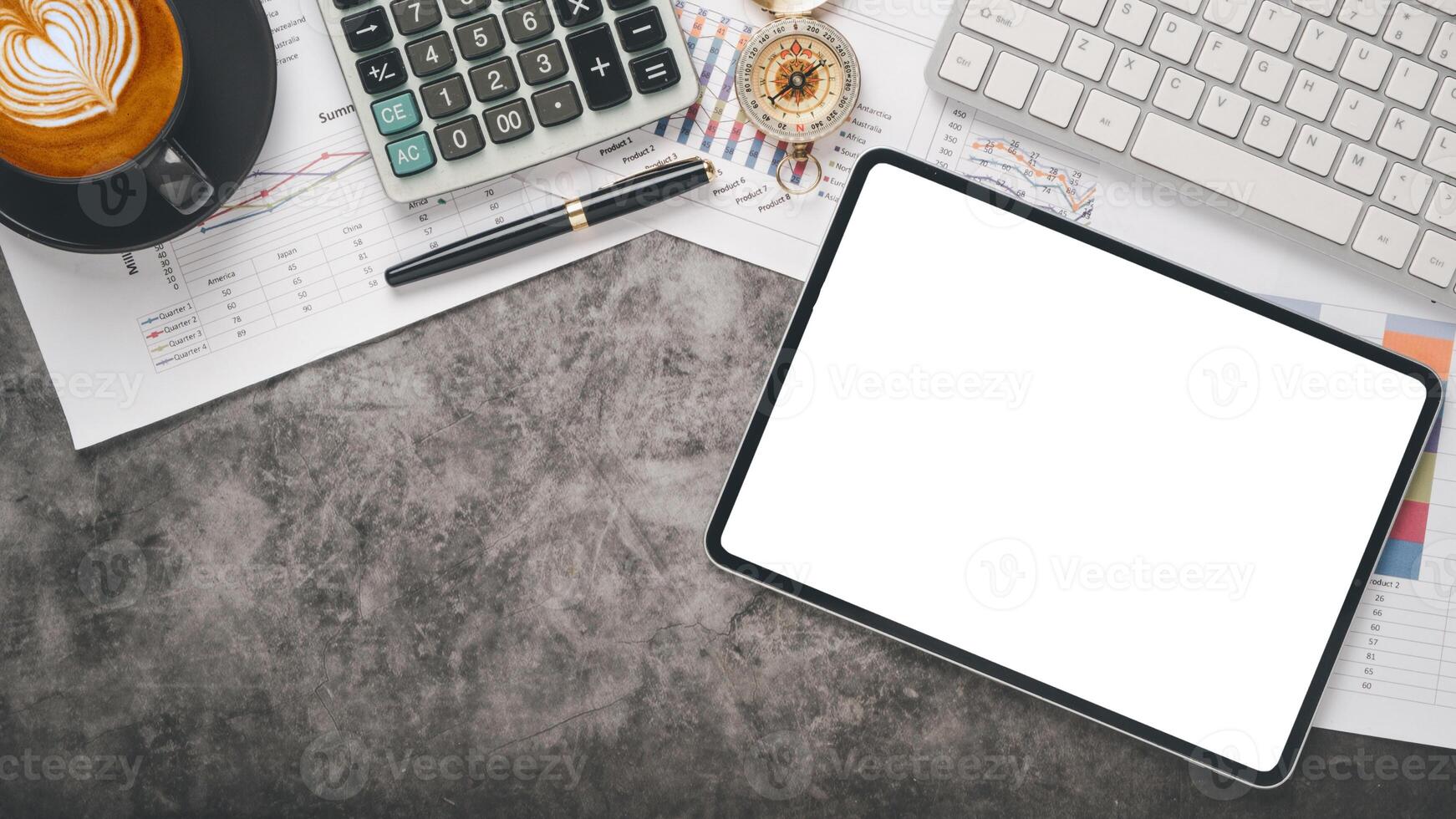 An organized desk featuring a blank tablet screen, financial documents, a cup of cappuccino, and office supplies. photo