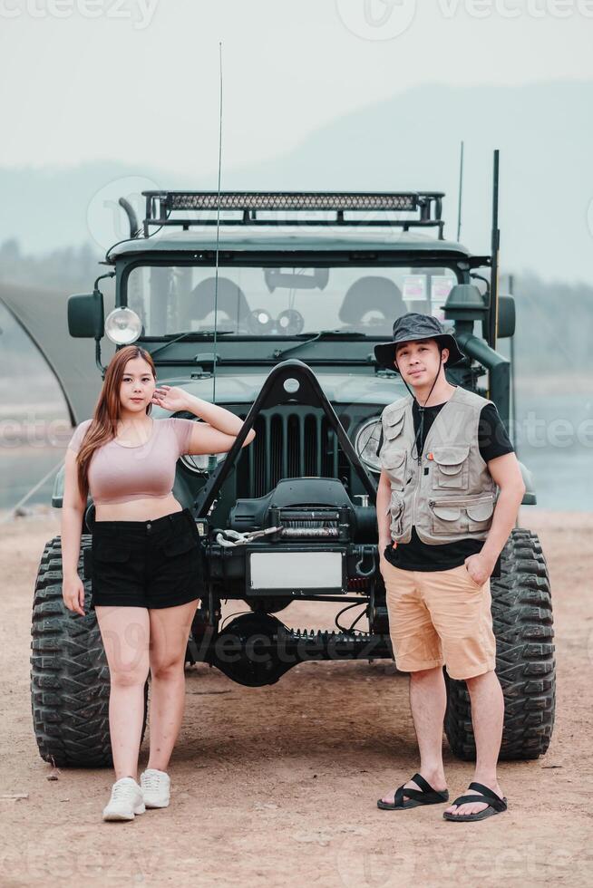 Young couple poses confidently beside their rugged ff-road car, ready for an adventure in the great outdoors. photo
