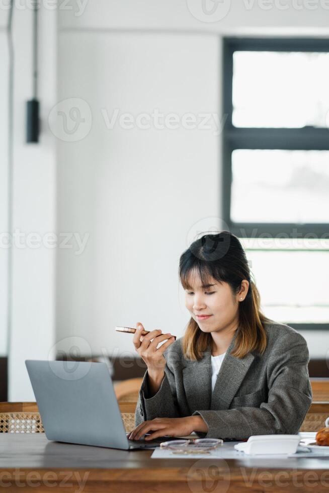 Casual businesswoman eating a snack during a focused work session on her laptop in a light-filled cafe. photo