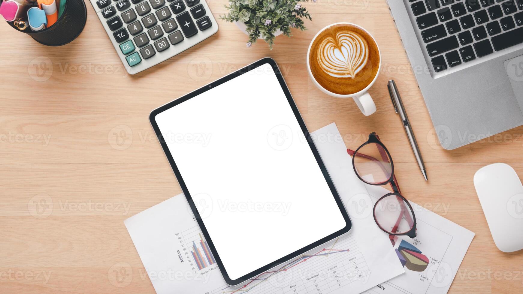 A tablet sits on a desk with a cup of coffee and a pen. The tablet is empty, and the coffee cup has a heart design on it. The scene suggests a moment of relaxation or contemplation photo