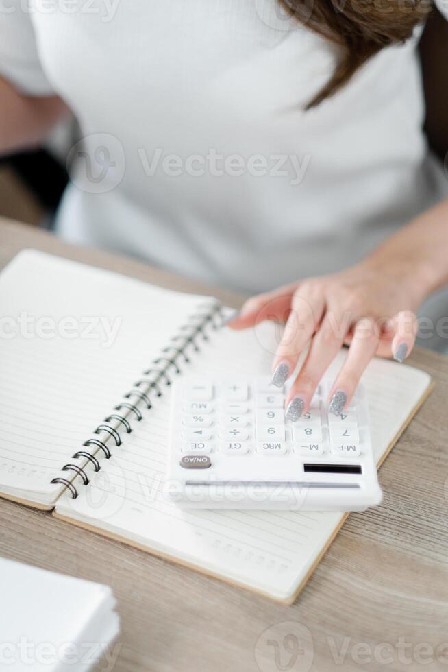 Close-up of a professional's hands using a calculator on a desk with paperwork. photo
