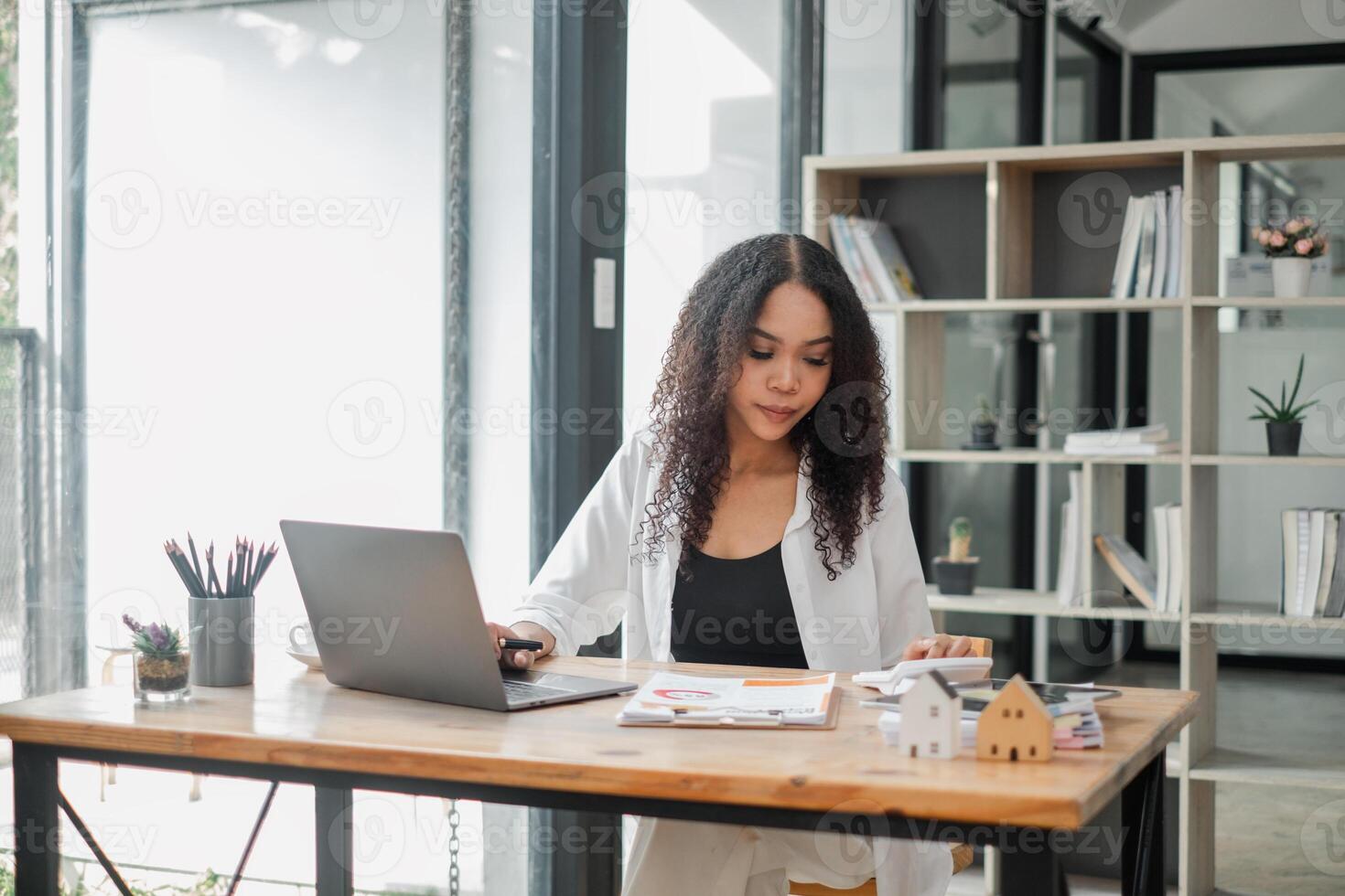 Real estate agent attentively examines property listings on her laptop in a stylishly furnished office, symbolizing professionalism and dedication. photo