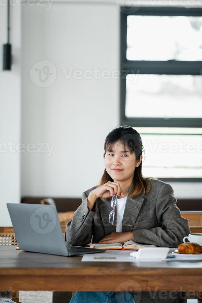 Confident entrepreneur takes a moment from working on her laptop in a cafe, reflecting on her next business move. photo