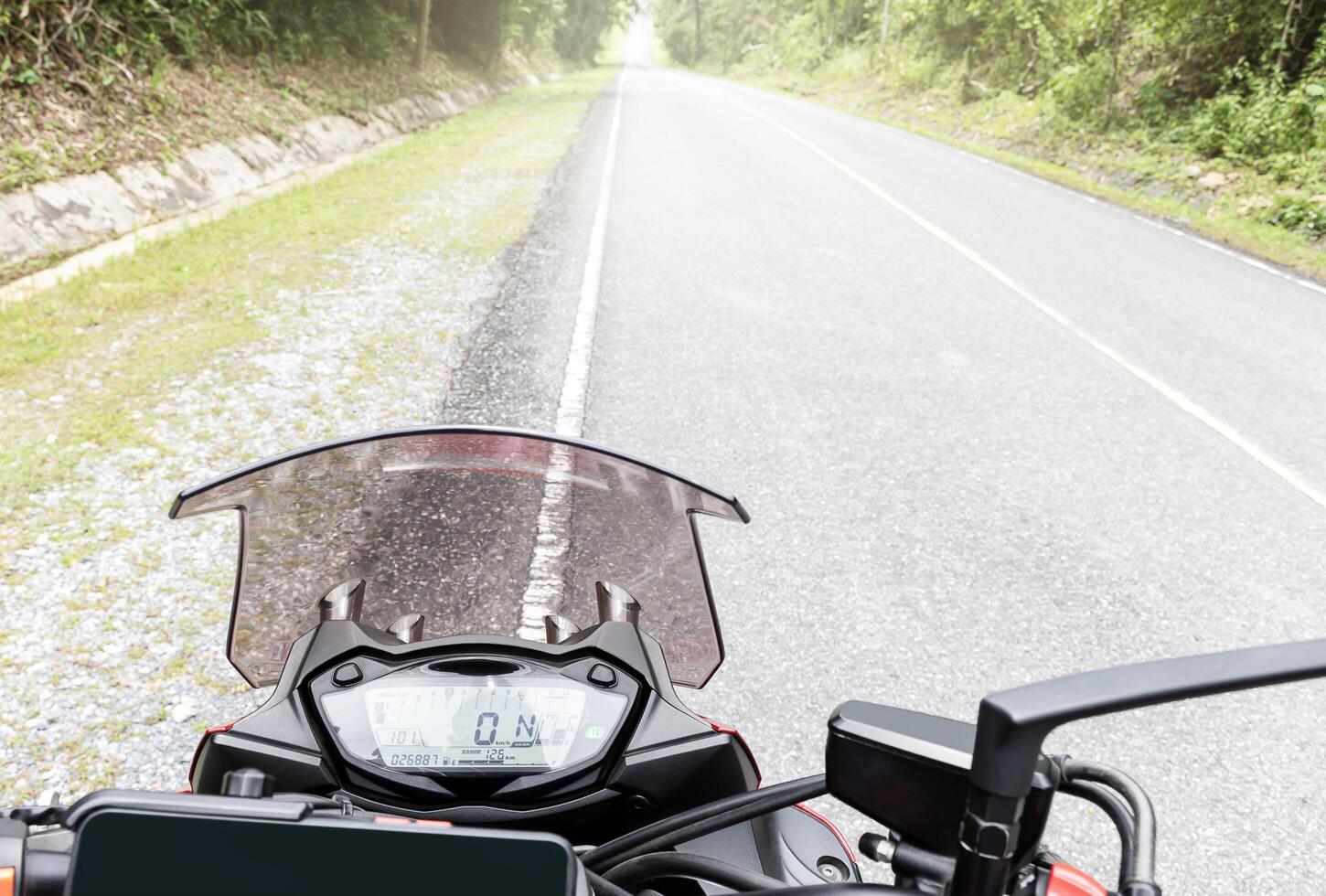 Handle bar motorcycle view with digital dashboard with road view background photo