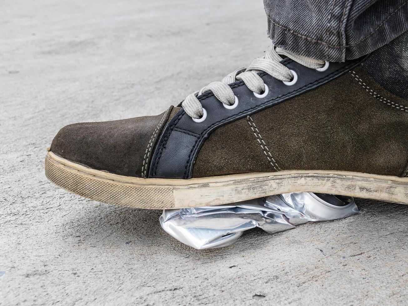 Man wear sneakers steps on silver aluminum can photo