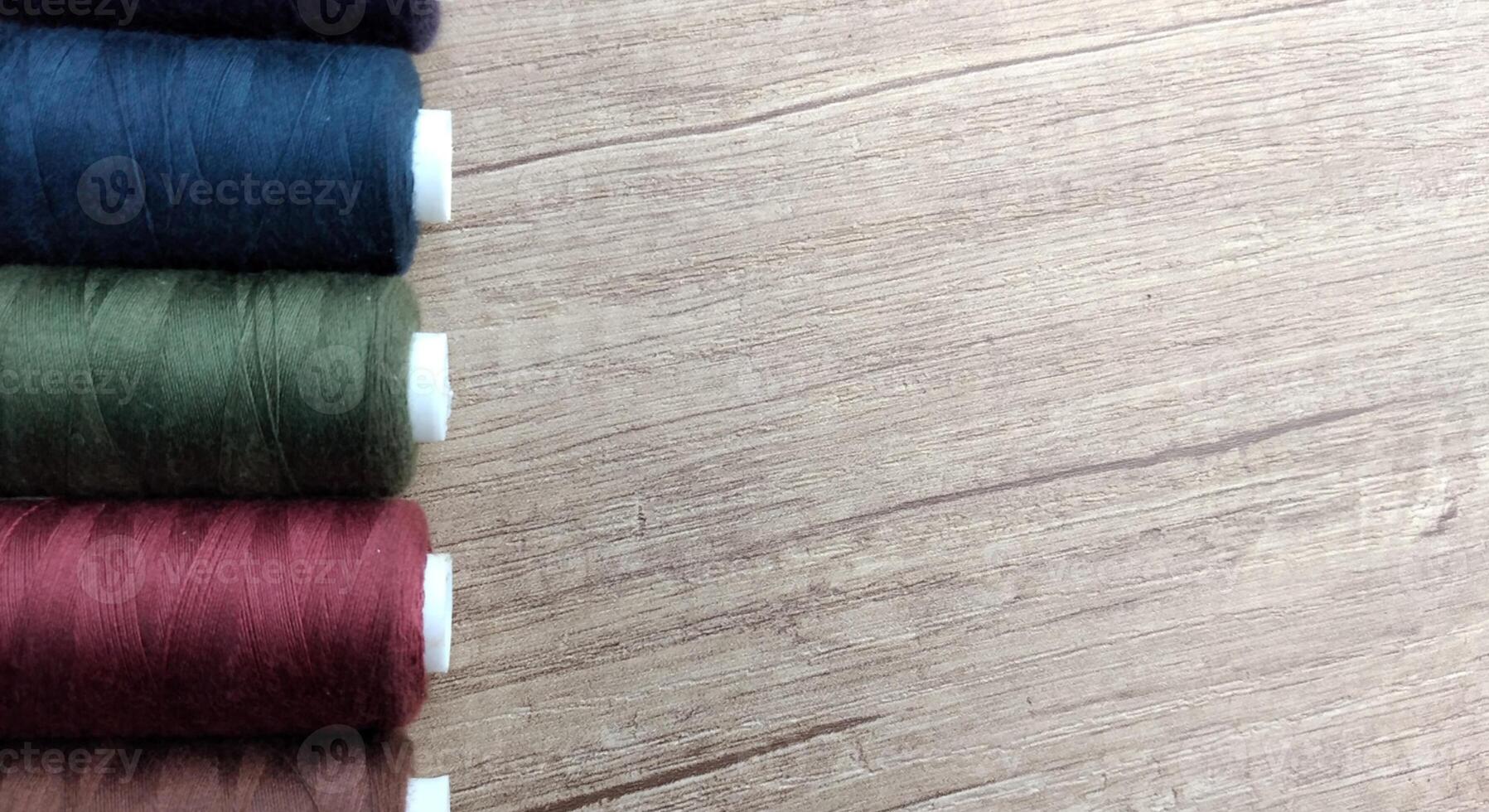 Spools of multicolored thread on wooden background with copy space photo