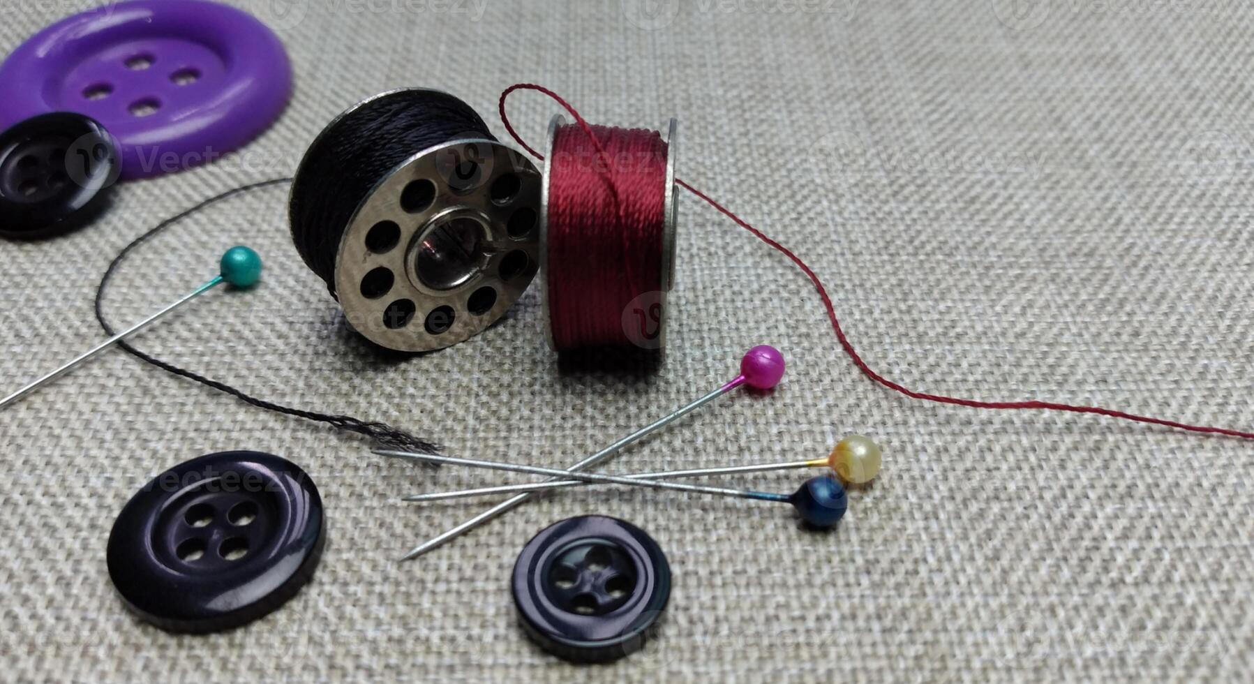 spool of thread, pins and buttons for sewing on a gray background photo