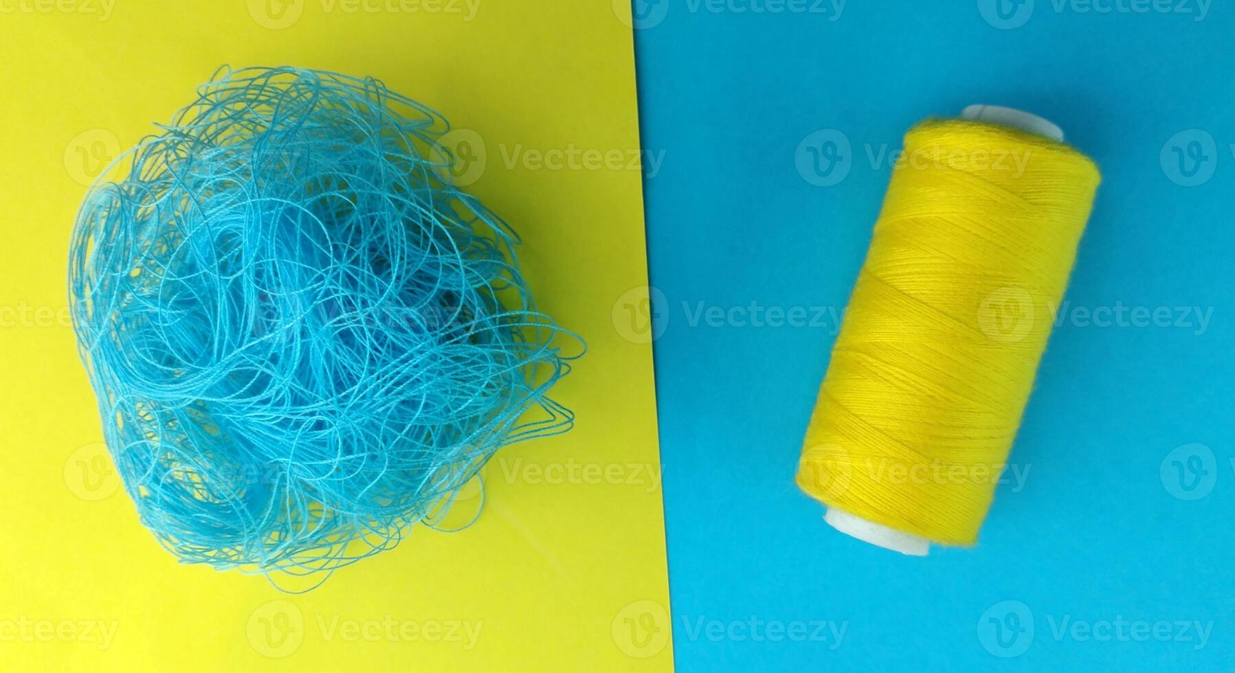 Spools of thread and a needle on a yellow and blue background, Contrast consept photo