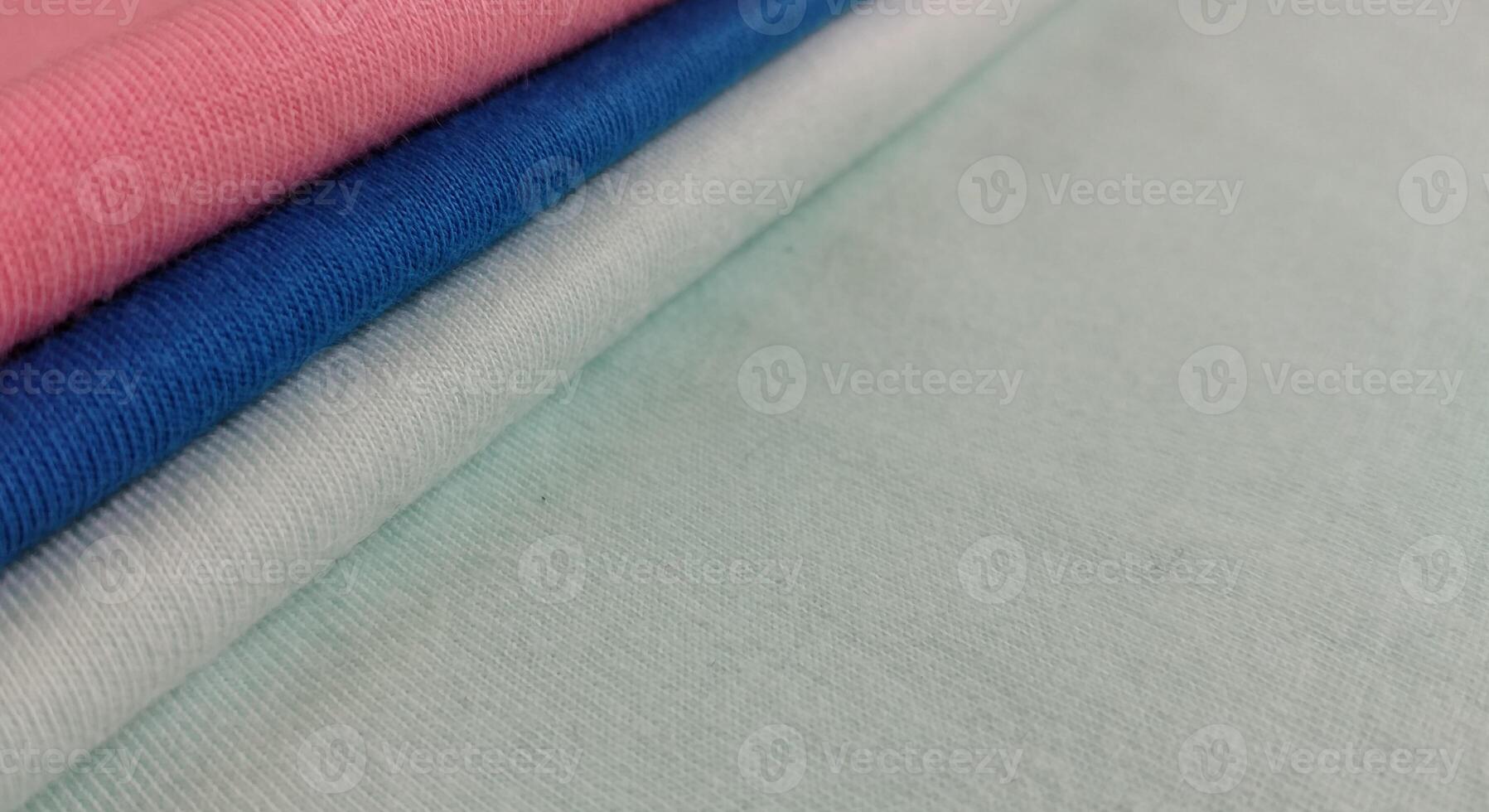 Fabric samples in different shades of blue and pink, closeup on green background photo