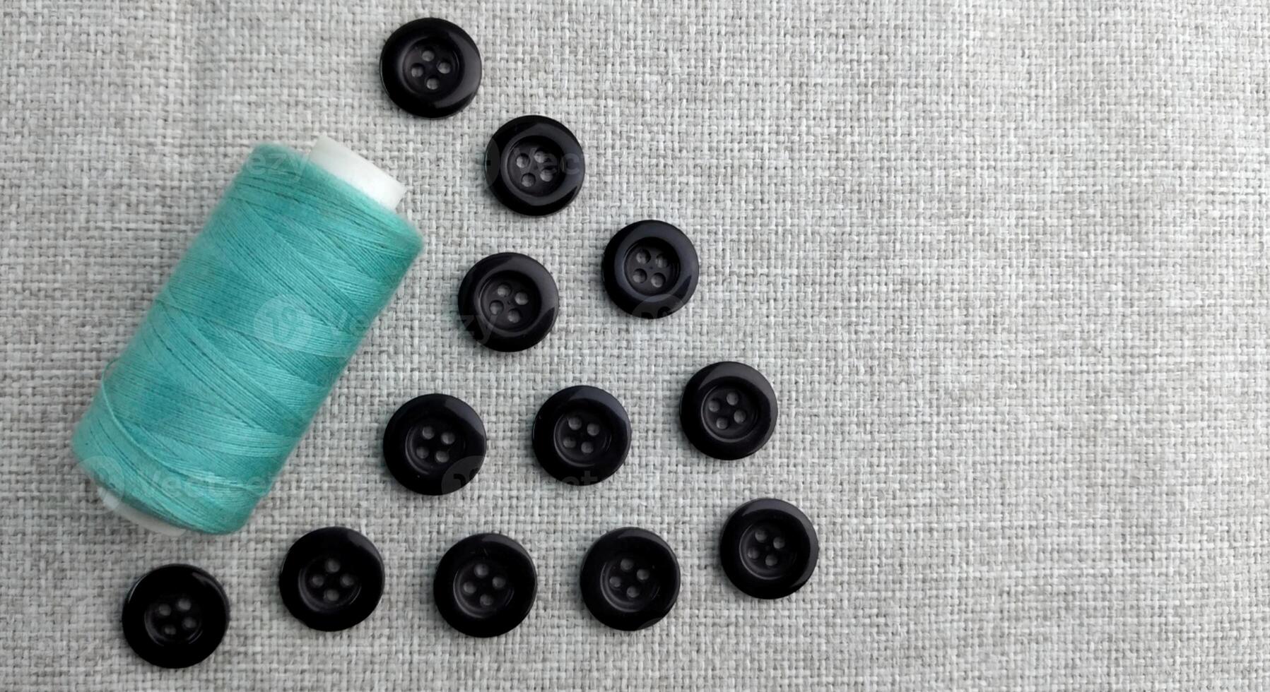 Spools of thread and buttons on a gray background, top view photo