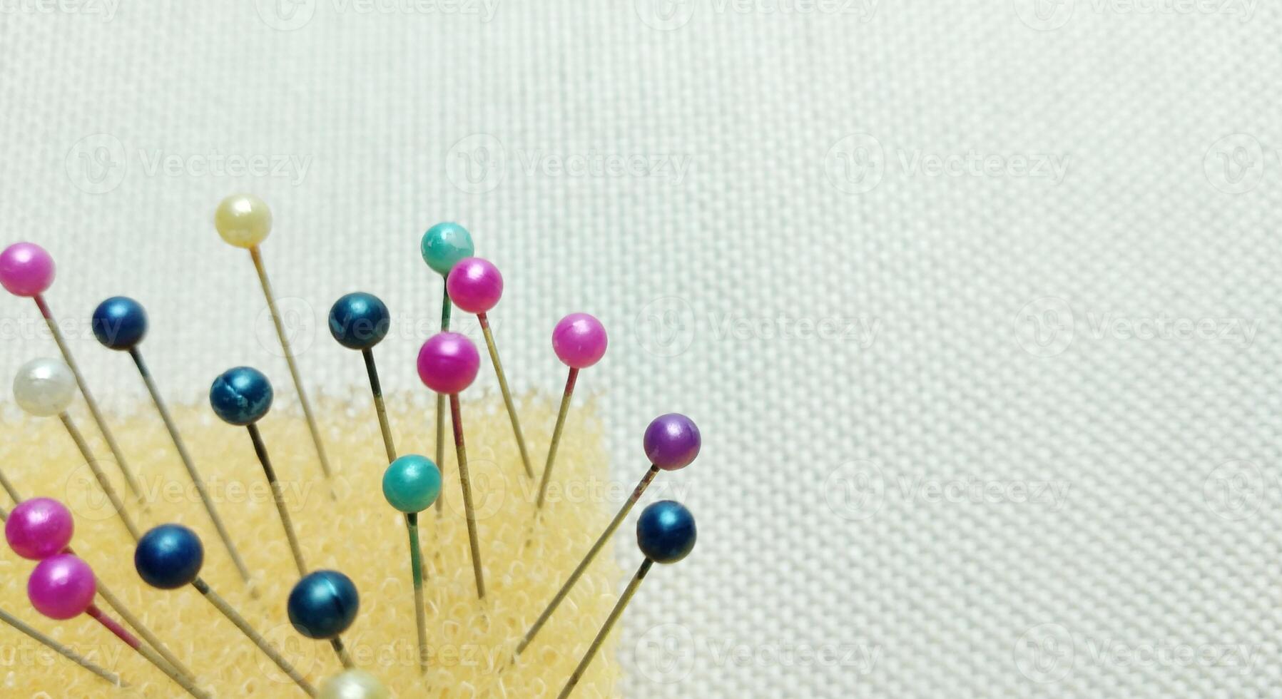 Colorful sewing pins on white fabric background with copy space for text photo