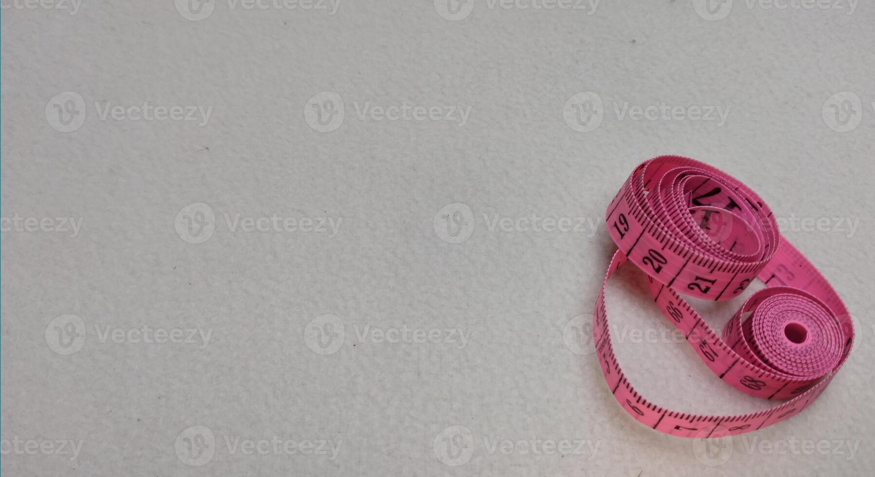 Pink measuring tape isolated on white background with copy space for text. photo