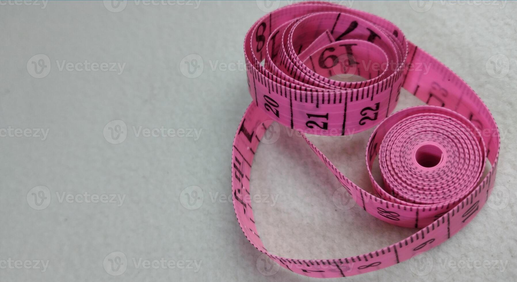 Pink measuring tape isolated on white background with copy space for text. photo