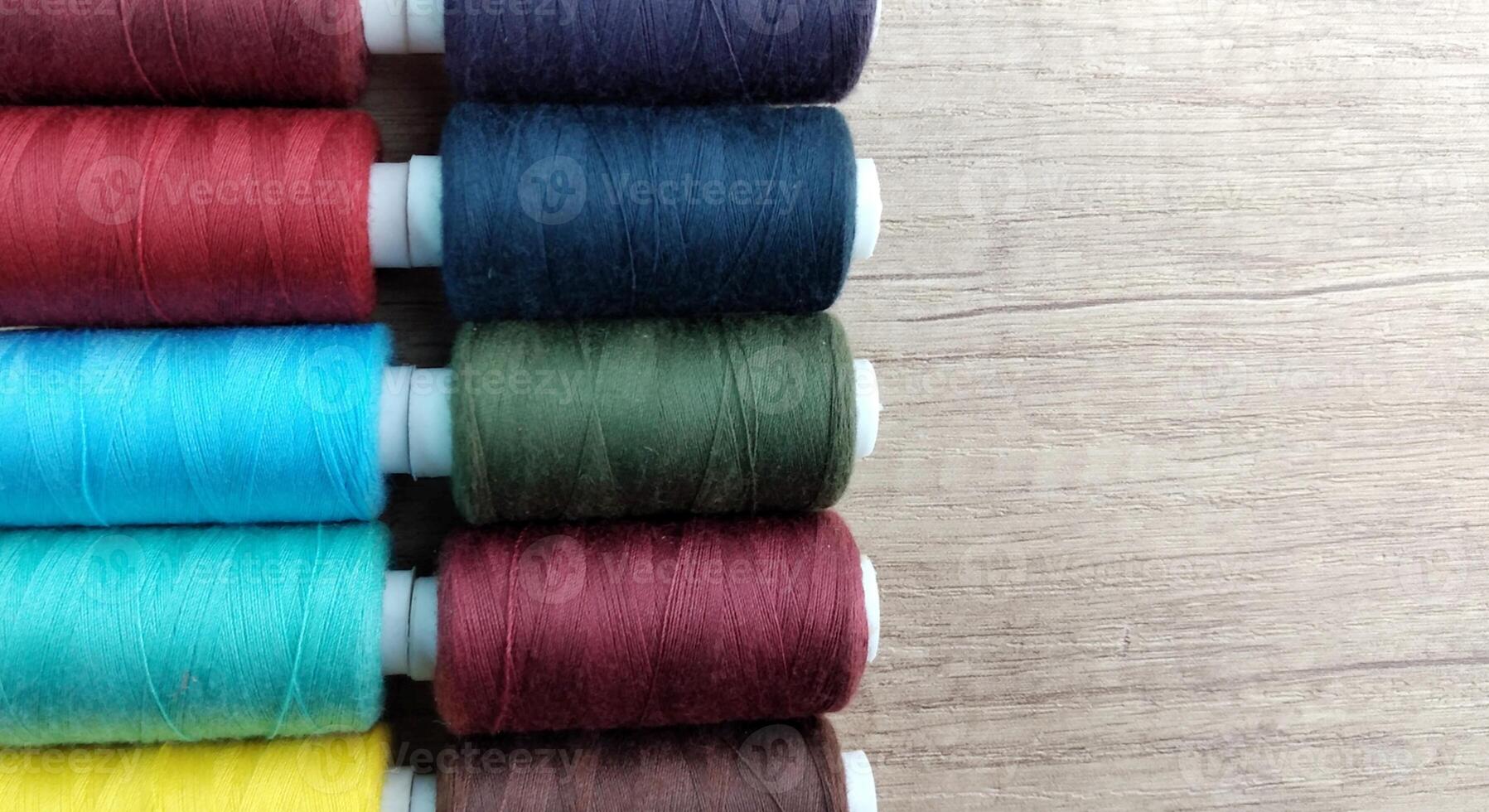 Spools of multicolored thread on wooden background with copy space photo
