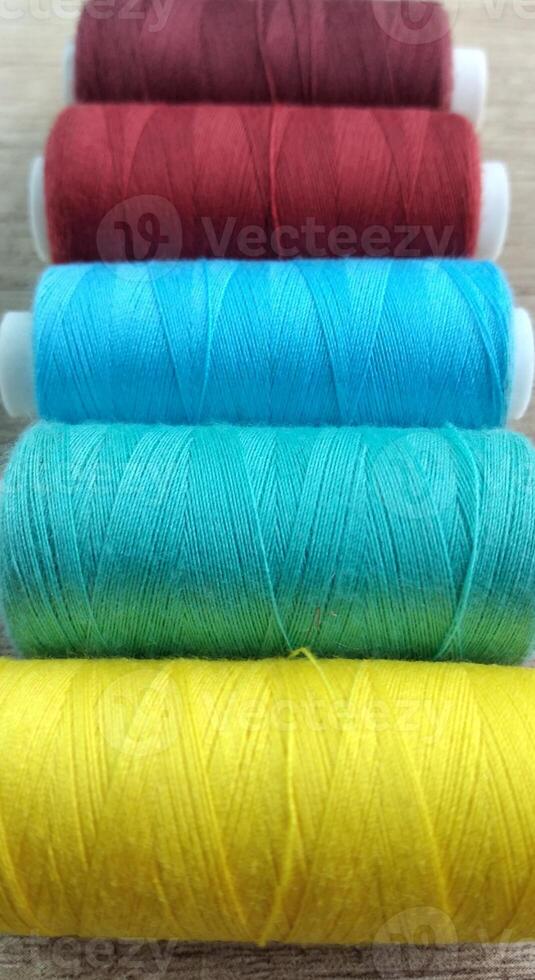 Spools of multicolored thread on wooden background with copy space photo