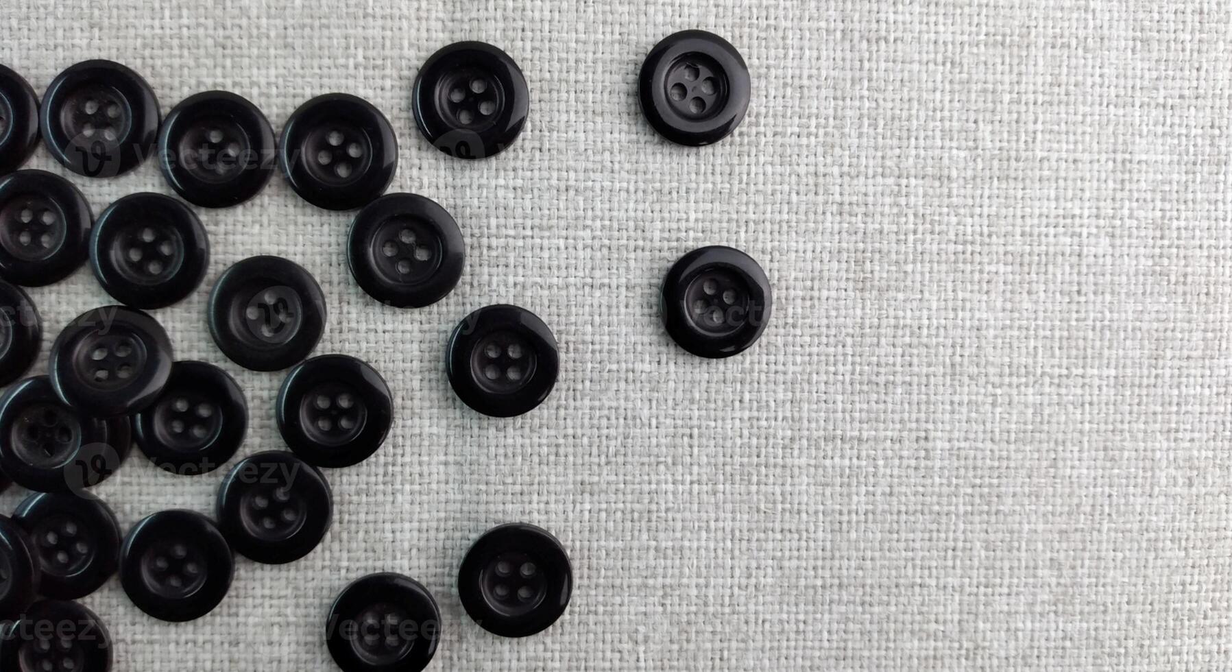 Black sewing buttons on white fabric background. Flat lay, top view. photo